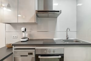 A modern kitchen with a built-in oven, a coffee machine, a stainless steel sink, and a range hood.