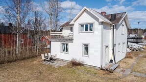 Une maison blanche à deux étages, dotée d’un petit porche et d’un garage.