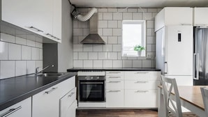 Une cuisine moderne avec des armoires blanches, un comptoir noir, un four encastré et une hotte de cuisinière en acier inoxydable.