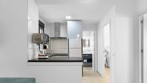 A modern kitchen with white cabinetry, a black countertop, and a built-in microwave. - Apartment 'Bellamar 6 Apartamento 2Dormitorios' with Wi-Fi and Air Conditioning (Barbate)