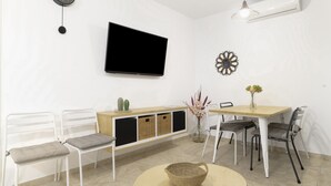 A modern living room with a flat-screen TV, white furniture, a round table, and a decorative wall piece. - Apartment 'Bellamar 6 Apartamento 2Dormitorios' with Wi-Fi and Air Conditioning (Barbate)