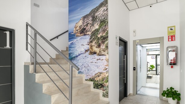 A staircase with a coastal mural, a fire alarm, and a potted plant in a modern interior. - Apartment 'Bellamar 6 Apartamento 2Dormitorios' with Wi-Fi and Air Conditioning (Barbate)
