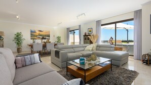 Un salon moderne comprenant un canapé, une table basse en verre et un coin repas avec une table et des chaises.
