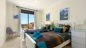 Une chambre avec deux lits, une chaise, un bureau et une fenêtre donnant sur un beau paysage.