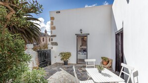 A courtyard with stone flooring, white furniture, and potted plants. - Vacation Home 'Casa Doña Carmen' with Mountain View, Private Terrace and Wi-Fi (Betancuría)