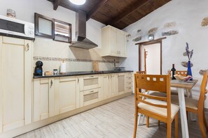 A kitchen with wooden cabinets, a microwave, a stove, and a dining area with chairs and a table.