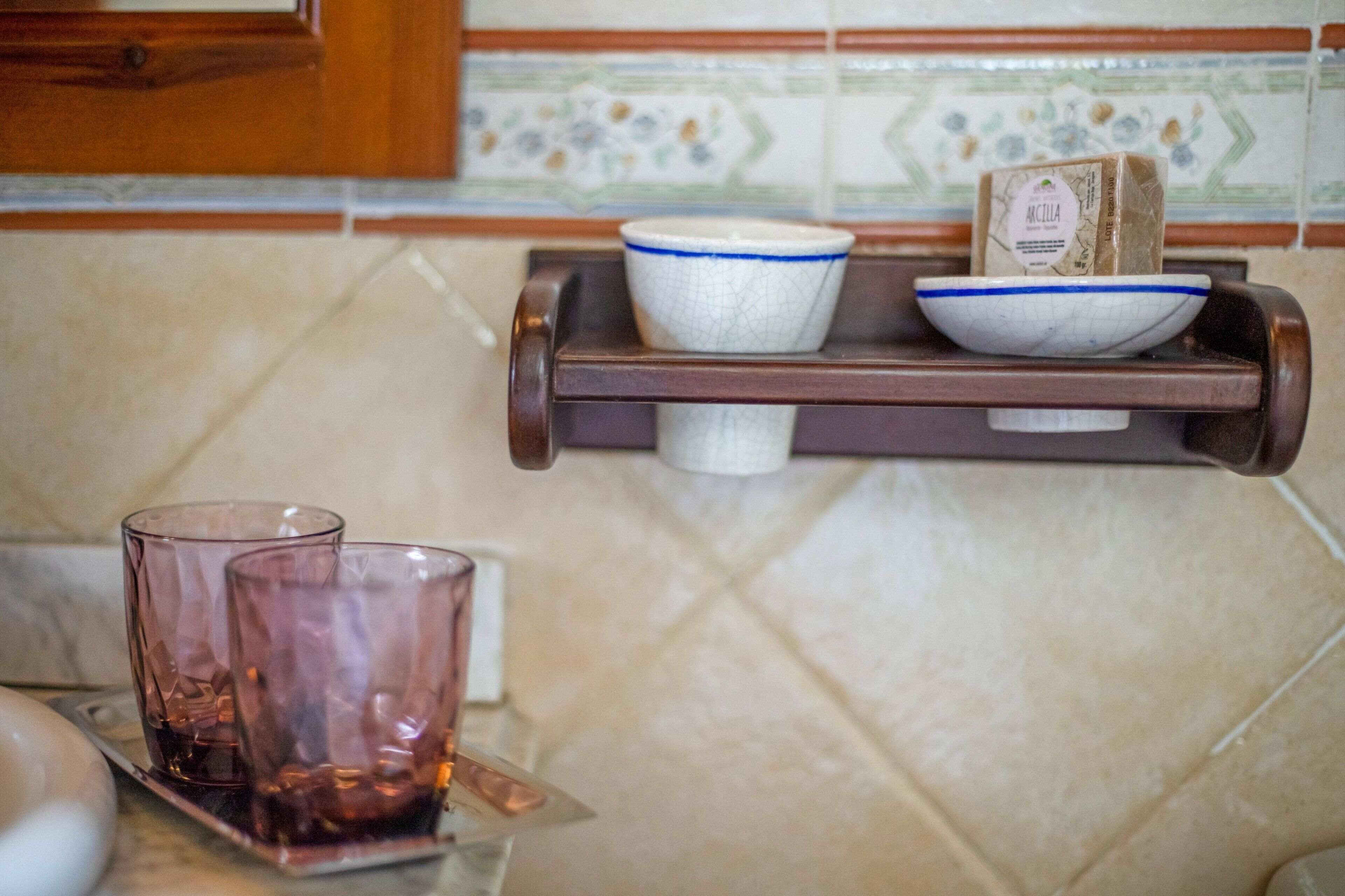 Una encimera de cocina con una bandeja que contiene una barra de jabón, dos vasos y un bol.