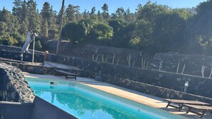 A swimming pool with a stone wall, a bench, and a wooden deck.