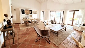 A spacious living area with a sofa, coffee table, and dining set.