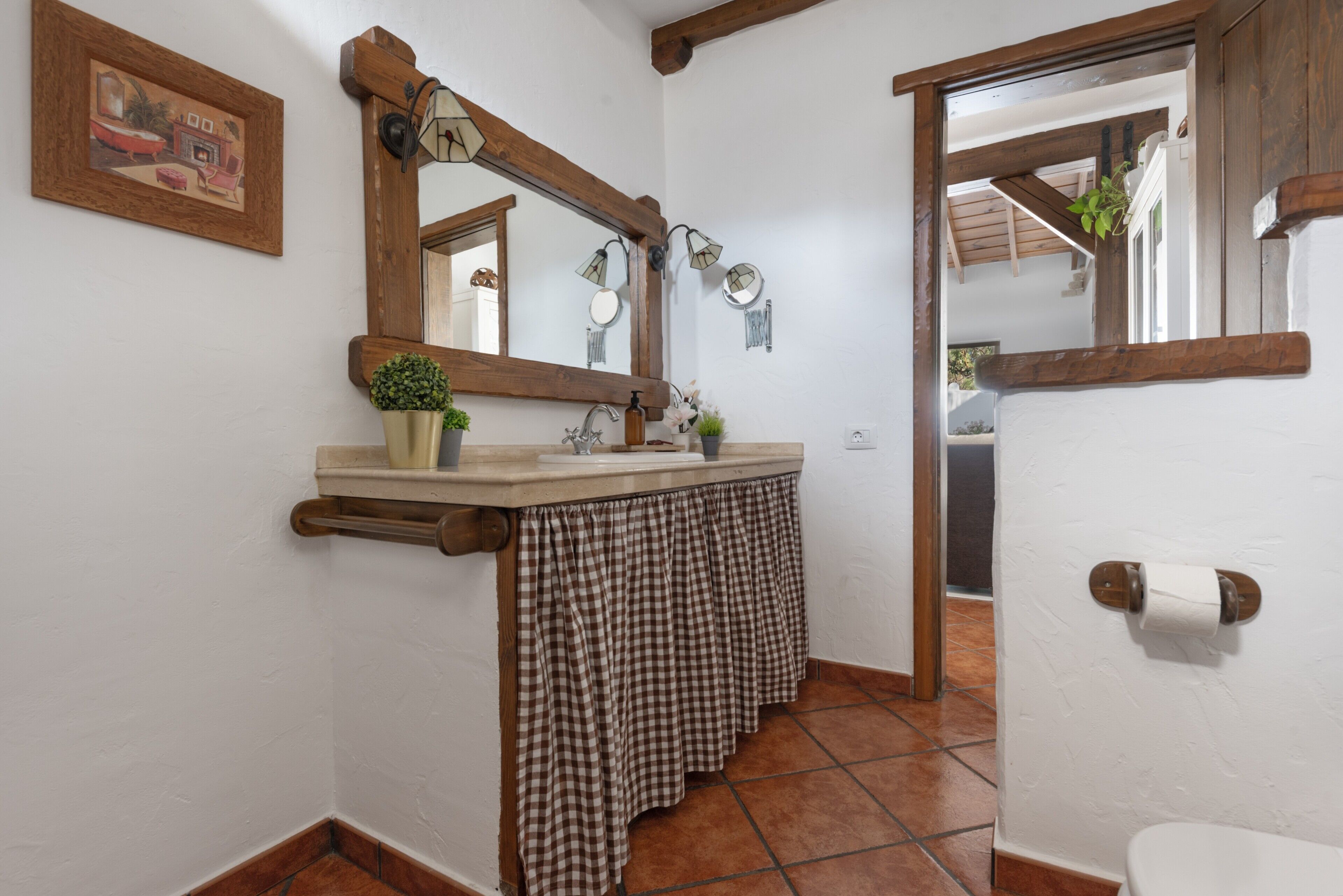 A bathroom with a wooden vanity, a large mirror, a towel rack, and a toilet paper holder.