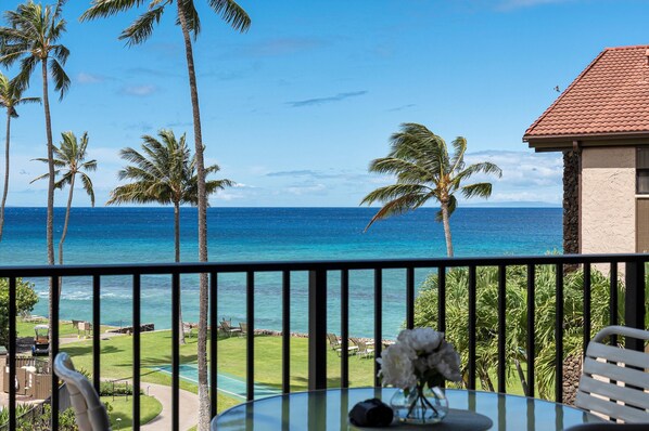 Relax on the balcony with a serene view of the tropical beach and palm trees.