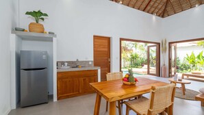 A modern kitchen with a stainless steel refrigerator, wooden cabinets, and a dining area with a wooden table and chairs. - Villa Lounes 1 (Tabanan)
