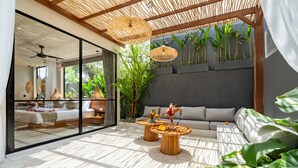 A modern living room with a glass wall, a ceiling fan, and a large plant. - Villa Saya (Canggu)