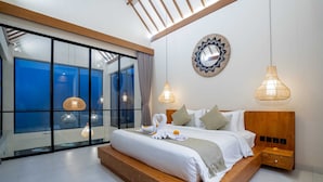 A modern bedroom with a large bed, a wooden headboard, and a view through floor-to-ceiling glass windows. - Villa Saya (Canggu)