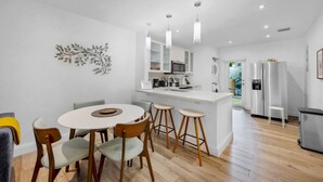 A modern kitchen with white cabinets, a central island, and bar stools.