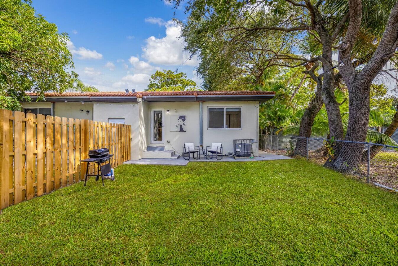A house with a fenced backyard, a patio with outdoor furniture, and a garage.