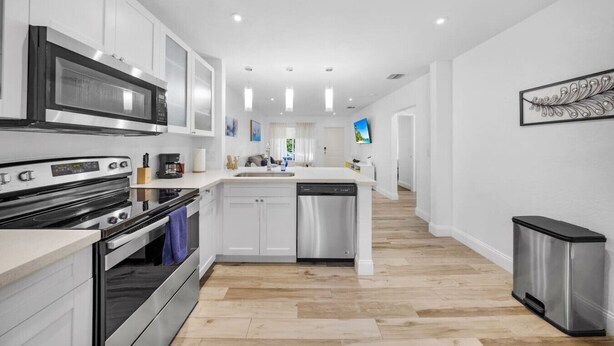 A modern kitchen with white cabinetry, stainless steel appliances, and a central island.