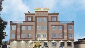A multi-story hotel with a modern design, featuring a central entrance with a glass facade and a sign above. - Al Zahra Hotel Apartments (Ras Al Khaimah)