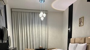 A modern hotel room with a large bed, a flat-screen TV, a bedside table, and a decorative rug. - Al Zahra Hotel Apartments (Ras Al Khaimah)