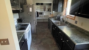 A kitchen with dark cabinets, a stainless steel refrigerator, a microwave, and a stove.