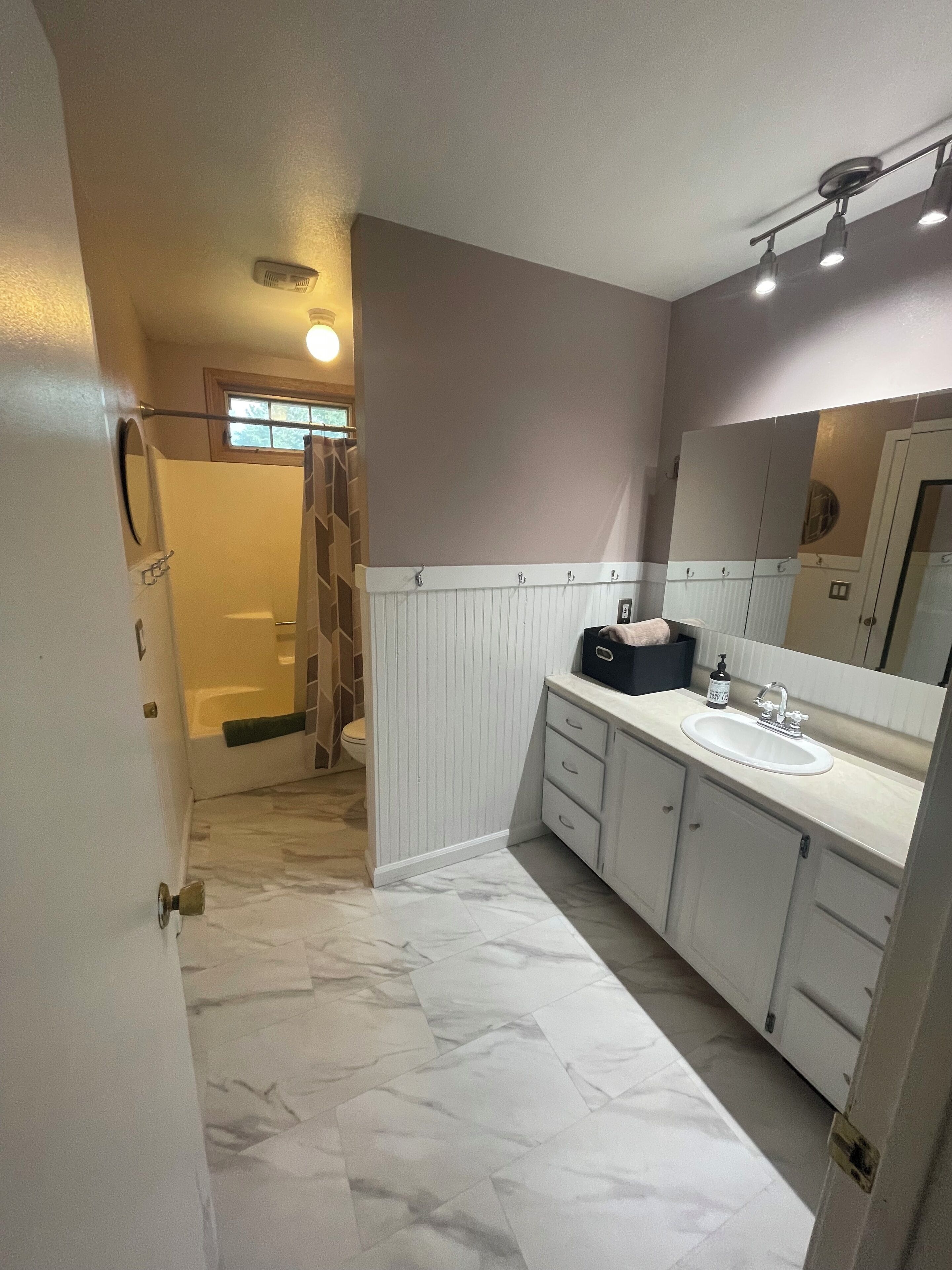A bathroom with a white vanity, a large mirror, and a shower area.