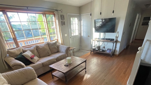 A spacious living room with a large window, a sofa, a coffee table, and a television.