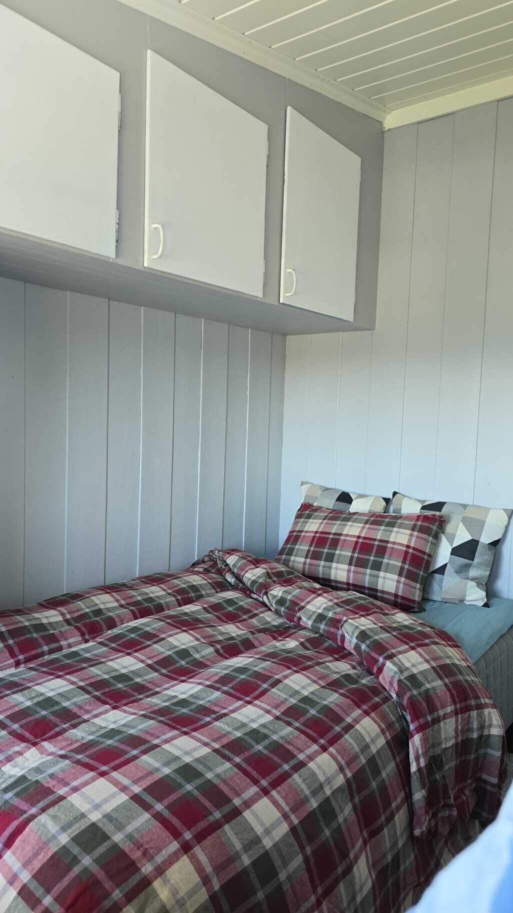 A bedroom with a bed, two cabinets, and a headboard.