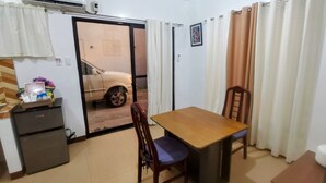 A compact room with a dining table, chairs, a small refrigerator, and an air conditioning unit. - Charming bungalow with AC and WiFi in peaceful Angeles (Angeles)