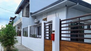 A modern two-story house with a white exterior, a wooden gate, and a mailbox. - Charming bungalow with AC and WiFi in peaceful Angeles (Angeles)
