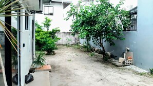 A narrow courtyard with a concrete path, potted plants, and a small tree. - Charming bungalow with AC and WiFi in peaceful Angeles (Angeles)
