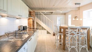 A kitchen with white cabinets, a wooden countertop, and a built-in brick oven. There is a staircase leading to another room. - Semi-detached House Waygaard West, Dagebull (Dagebuell)