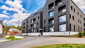 A modern building with a flat roof, multiple windows, and a stone base. - Plešivec by Interhome (Abertamy)