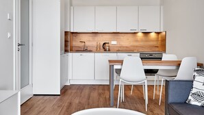 A modern kitchen with white cabinets, a wooden countertop, and a dining area with white chairs. - Plešivec by Interhome (Abertamy)