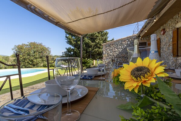 A dining table set for six with a clear view of a swimming pool and a stone wall in the background. - Villa can Mel in Buger by Home Villas 360 (Buger)