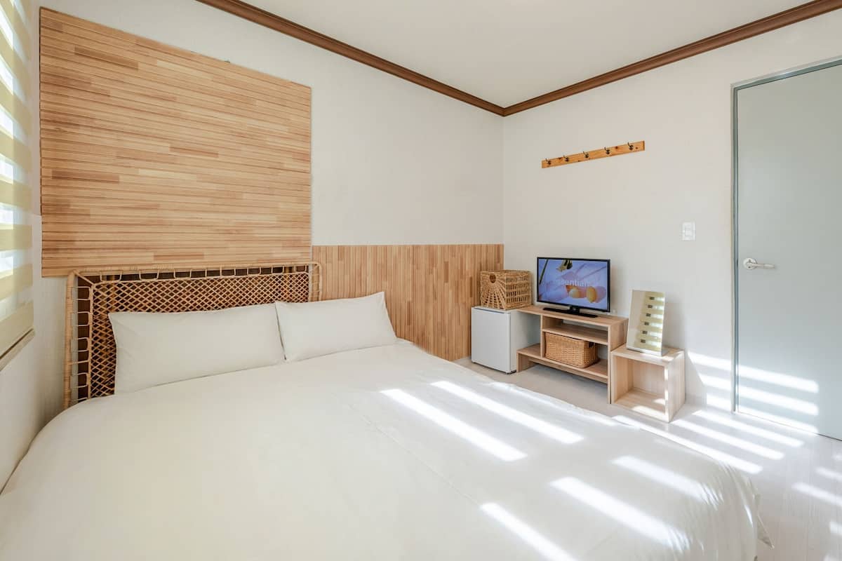 Un dormitorio con cama, televisión, armario y una mesita con cesta.