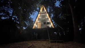 A triangular wooden cabin with a staircase leading up to a door, surrounded by trees. - Peaceful secluded cabin located near Horseshoe Lake  (Miller City)