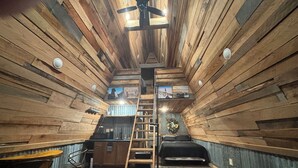 A cabin interior with a wooden interior, a staircase, a bed, a sofa, and a dining area. - Peaceful secluded cabin located near Horseshoe Lake  (Miller City)