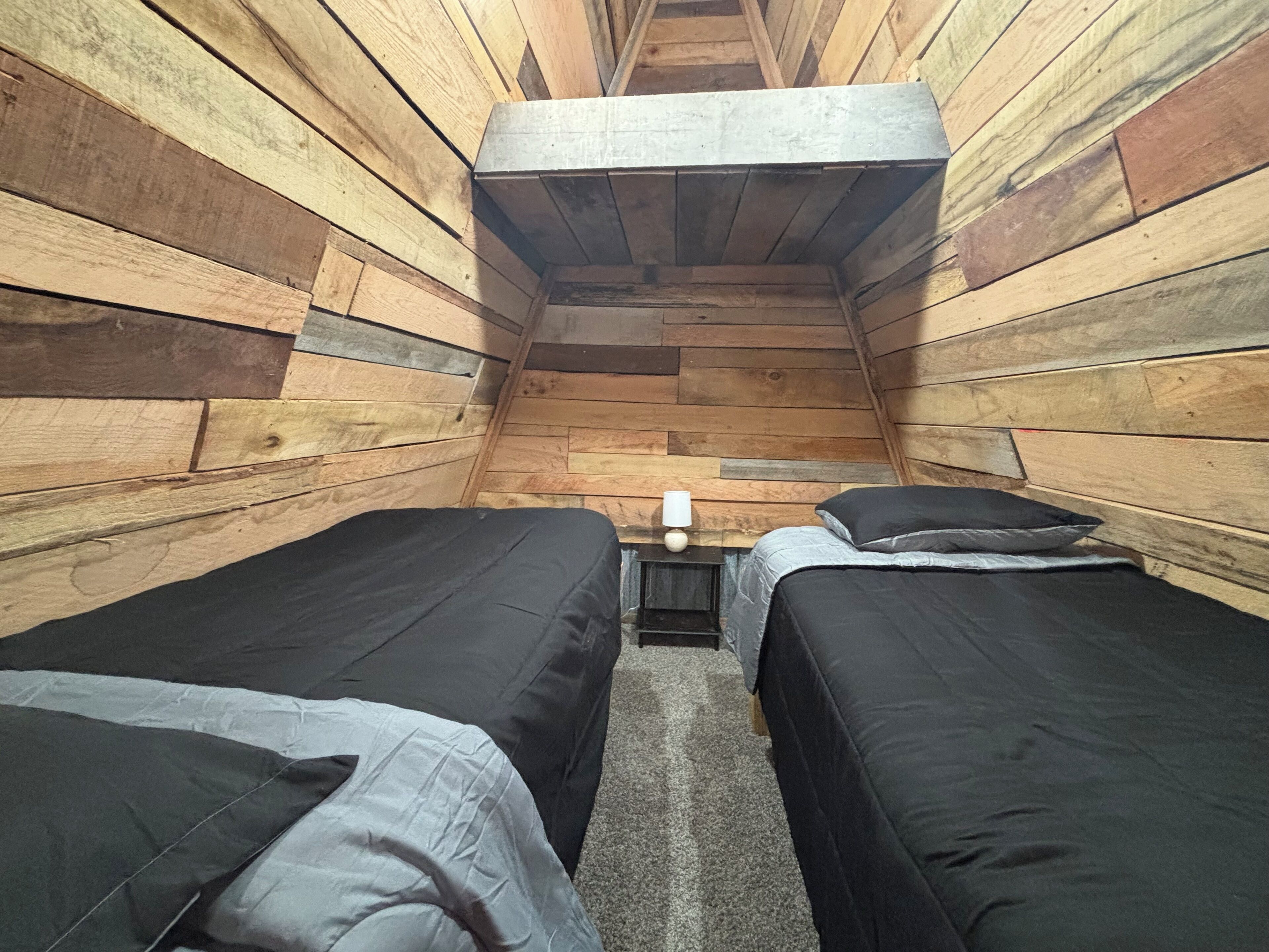 Une petite pièce, de taille modeste, avec des murs en bois et deux lits simples.