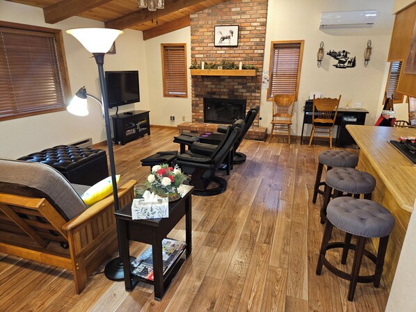 A cozy living room with a fireplace, wooden furniture, and a bar area. - Garden Cabin with Fenced Yard and AC (Pinetop)