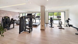 A modern gym with various exercise equipment, large windows, and a clean, spacious layout.