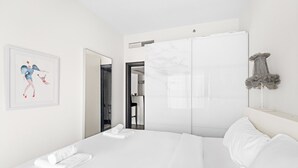 Una habitación de hotel moderna con una cama grande, un armario y una obra de arte enmarcada en la pared.