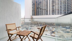 Un balcón con vista a una obra en construcción y un edificio de gran altura al fondo.
