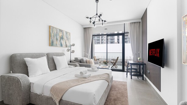 Una habitación de hotel moderna con una cama grande, televisión, balcón con vistas y zona de comedor.