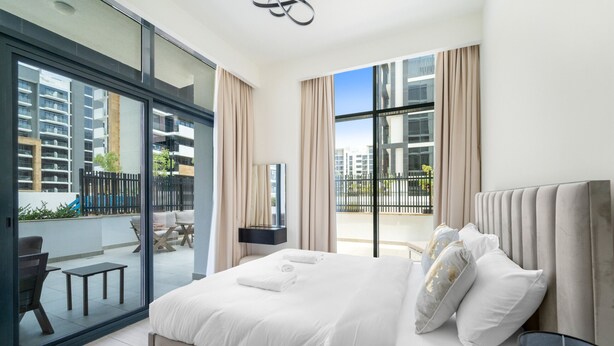 Moderni hotellihuone, jossa on suuri sänky, parveke, jolta on näkymä kaupunkiin, sekä ruokailutila ulkokalusteineen.
