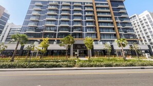 A modern multi-story hotel with a prominent entrance, balconies, and a landscaped front garden. - Modern Studio in Prime Meydan Area (Dubai)