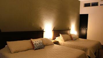 A hotel room with two beds, each with a headboard and bedside tables.