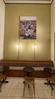 Un área de espera con un banco, dos mesas y una lámpara fijada a la pared.