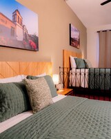 Una habitación de hotel con cama, mesita de noche, lámpara y dos cuadros en la pared.