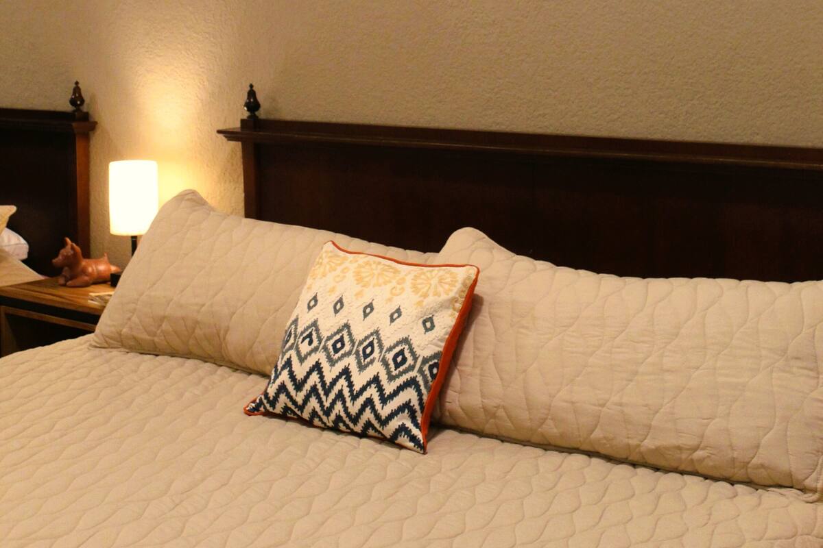 Cama bem arrumada com travesseiro estampado e cabeceira de madeira.
