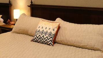 A neatly made bed with a patterned pillow and a wooden headboard.
